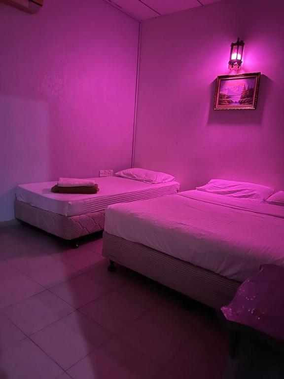 two beds in a room with purple lighting at G99 Hotel in George Town