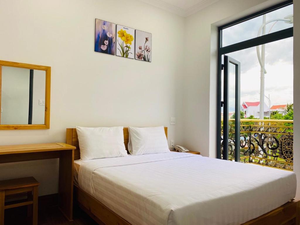 um quarto com uma cama branca e uma janela em Hotel Phạm Gia Phan Thiết em Phan Thiet