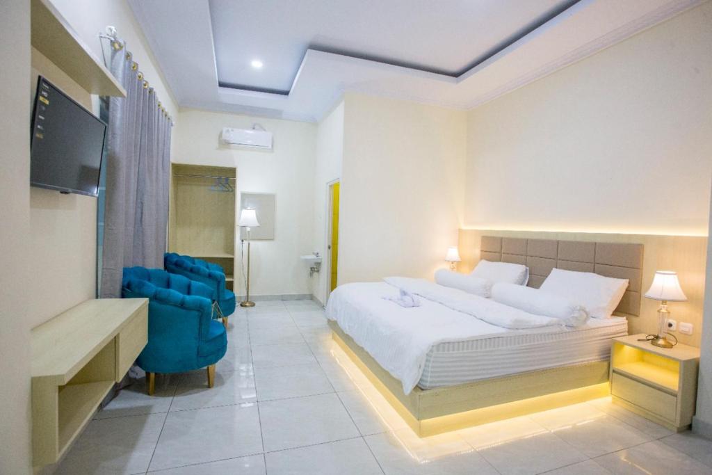 1 dormitorio con 1 cama blanca y 1 silla azul en HAYANA HOTEL, en Taruna