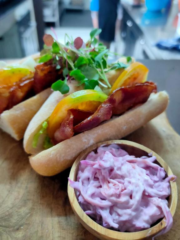 two hot dogs with bacon and coleslaw on a cutting board at Bale Sampan Boutique Bungalows in Gili Trawangan