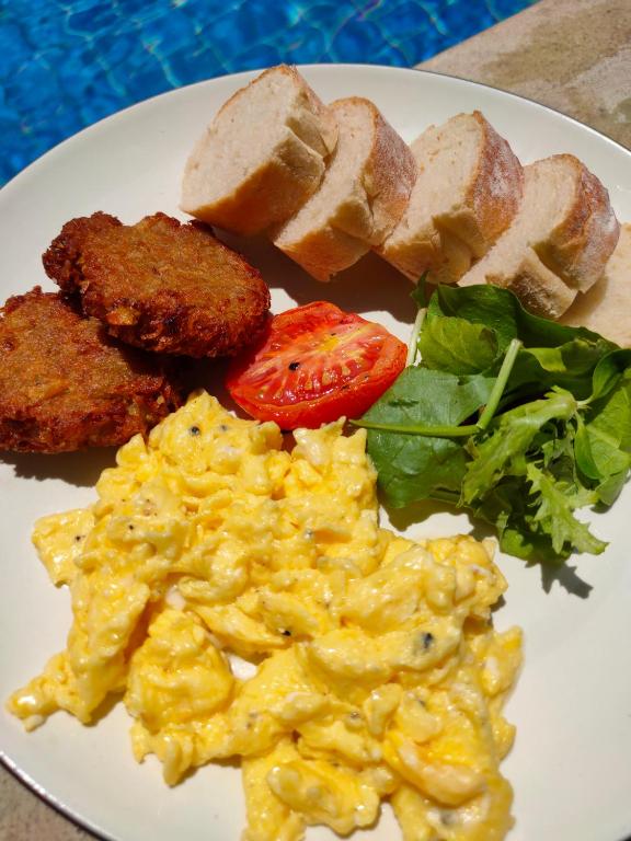 a plate of food with scrambled eggs and a salad at Bale Sampan Boutique Bungalows in Gili Trawangan