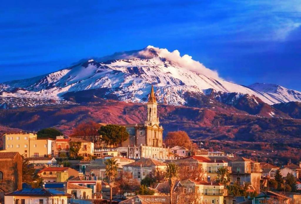 a city with a snow covered mountain in the background at Appartamento Etna in Trecastagni
