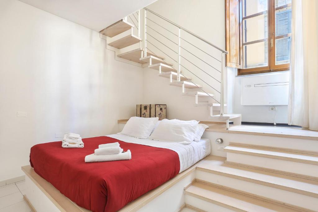 - une chambre dotée d'un lit avec une couverture rouge et des escaliers dans l'établissement Red Loft near Duomo-Hosted by Sweetstay, à Florence