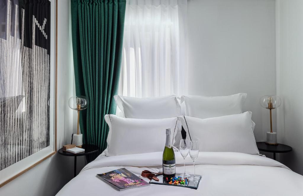 un letto bianco con una bottiglia di vino e una rivista di Townhouse Residence a member of Brown Hotels a Tel Aviv