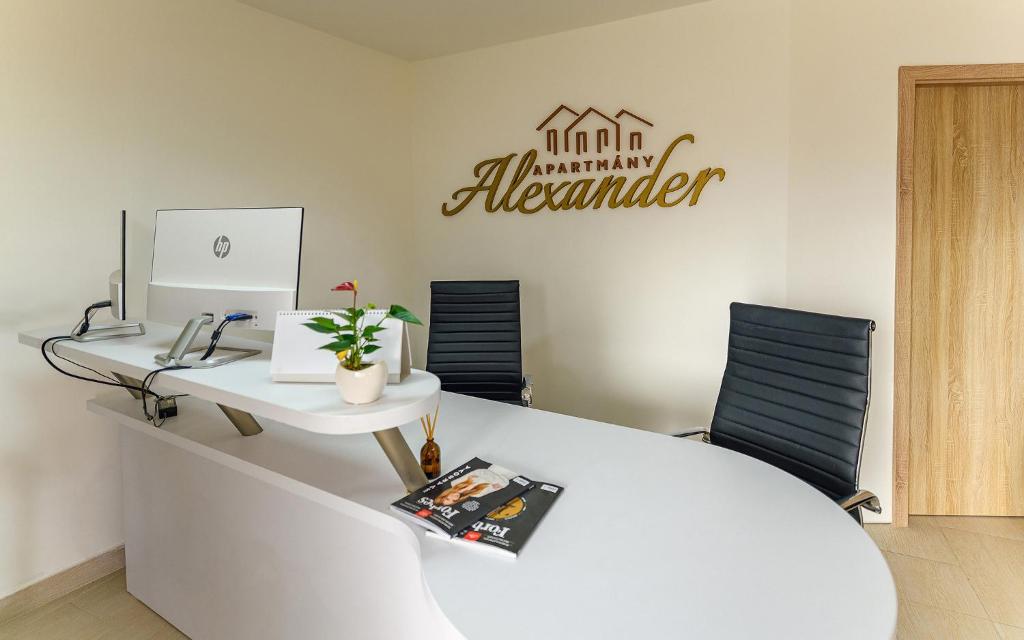 um escritório com uma secretária com um computador portátil e 2 cadeiras em Apartmány Alexander em Vrbov