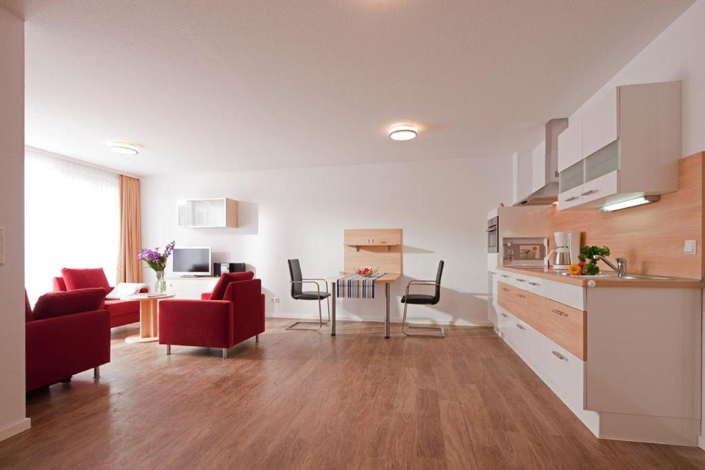 a kitchen and living room with red chairs and a table at Exquisit 3 in Norderney