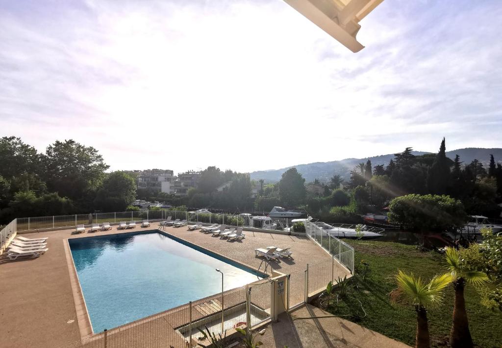 basen z leżakami i widokiem na miasto w obiekcie Appartement 5 en duplex, avec deux chambres - LES SUITES DE ROBINSON - Résidence avec piscine en bord de Siagne, à Mandelieu-La-Napoule w mieście Mandelieu-la-Napoule