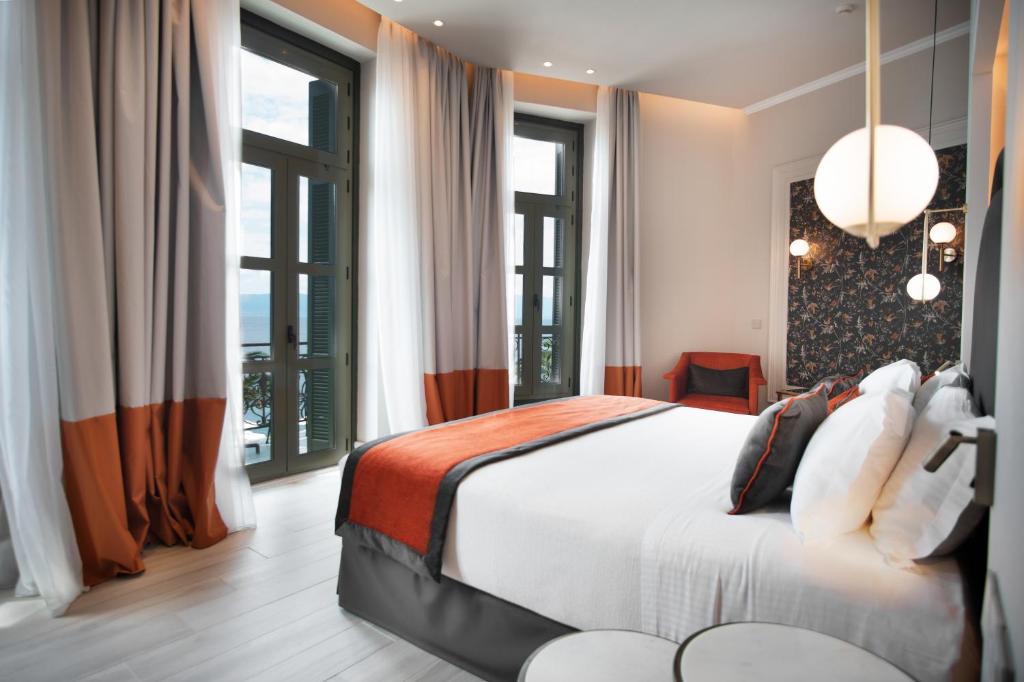 a bedroom with a large bed and large windows at Thermae Sylla Spa & Wellness Hotel in Loutra Edipsou