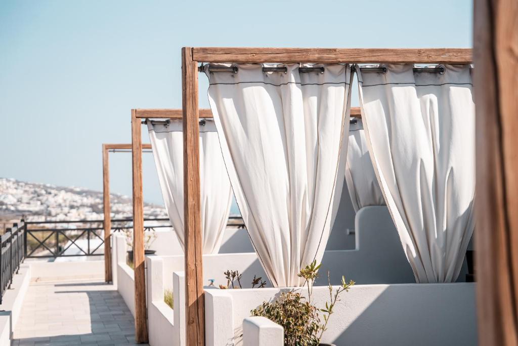a balcony with white curtains on a building at IfestAu.4 Suites in Fira