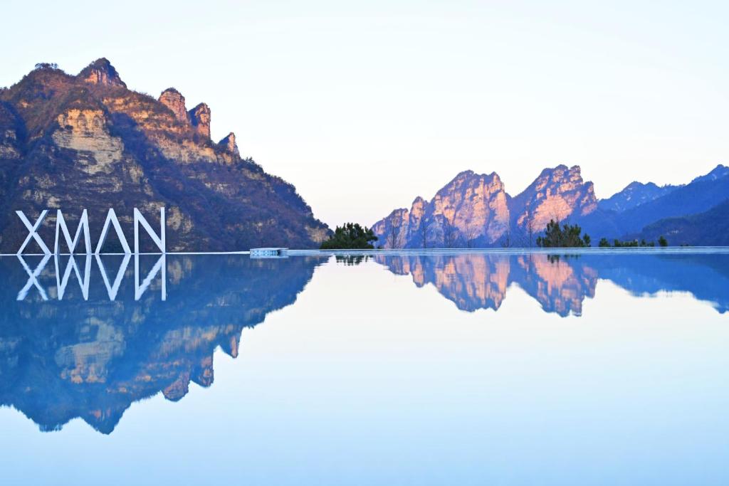 um reflexo de montanhas em um lago com a palavra xxx em XMAN Valley Sunrise Resort em Zhangjiajie
