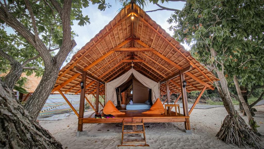 a bed in a tent in the middle of trees at Lihaga Island & Beach Club in Serai
