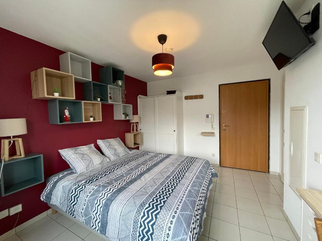 a bedroom with a bed and a red wall at Les Tuileries Eguisheim in Eguisheim