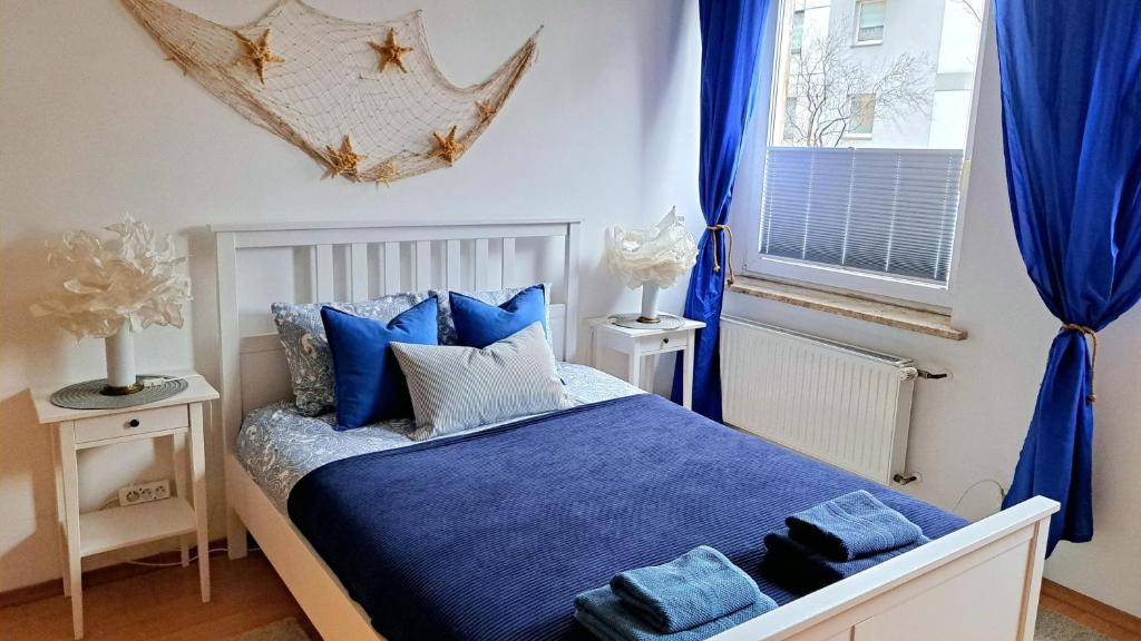 a bedroom with a bed with blue sheets and blue curtains at Sea Side Apartment in Gdańsk
