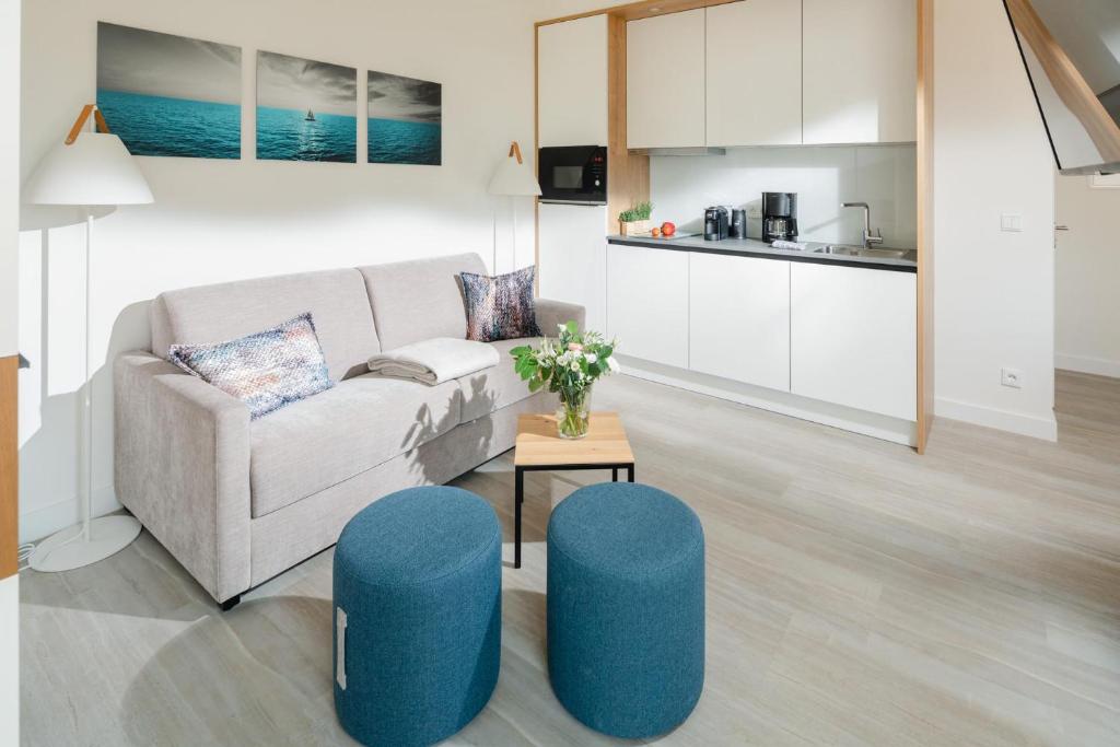 ein Wohnzimmer mit einer Couch und blauen Hockern in der Unterkunft Nordstrandperle Ap H7 in Norderney