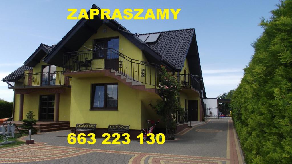 a yellow house with a black roof at Pokoje typu Studio OLSZYNA in Ustronie Morskie