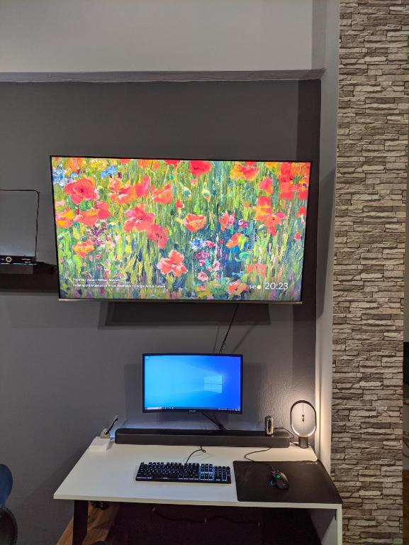 a desk with a computer and a monitor on a wall at Spyros's Home in Tríkala