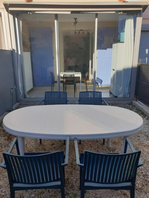 une table blanche et des chaises sur une terrasse dans l'établissement Studio 4 personnes avec jardinet à 2 pas des plages 