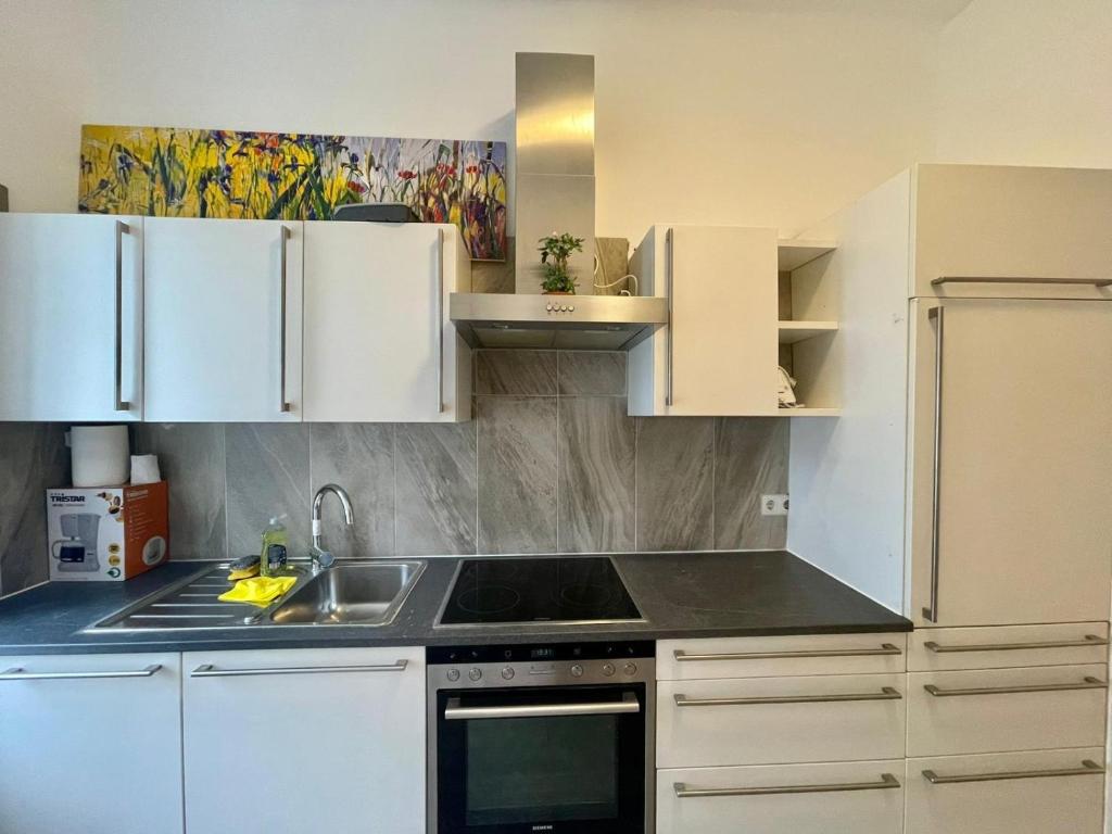 a kitchen with white cabinets and a stove top oven at Deluxe Studio 3P TH in Vienna