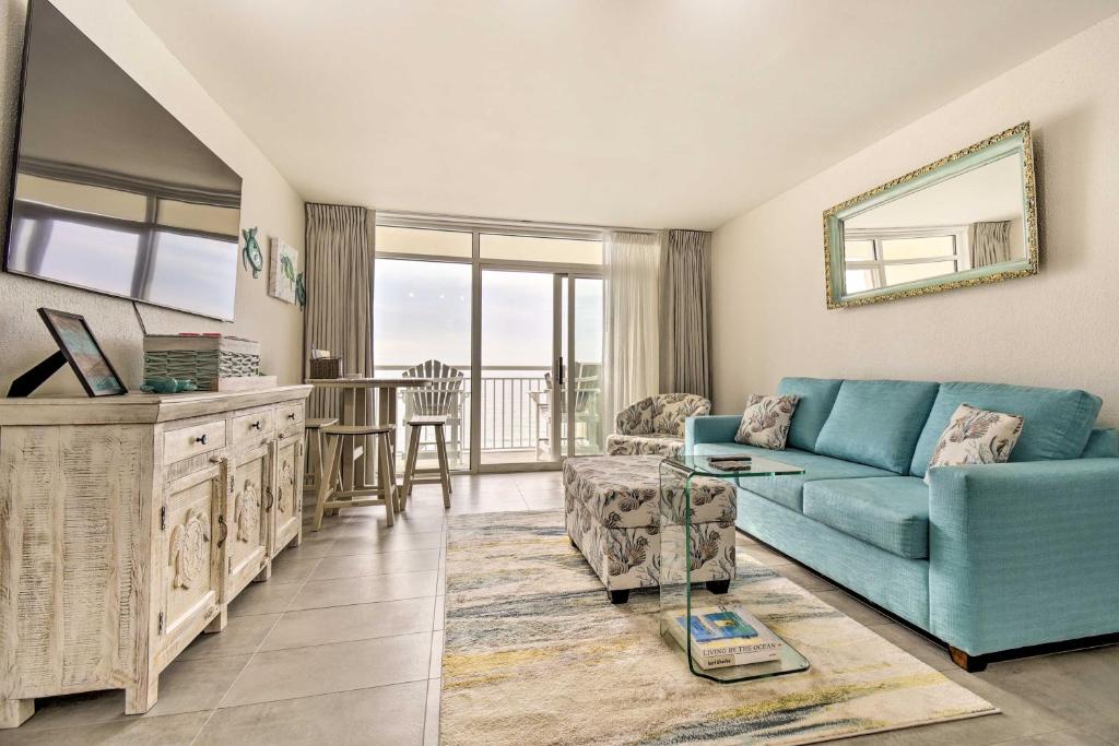 Oceanfront Resort Condo in North Myrtle Beach في ميرتل بيتش: غرفة معيشة مع أريكة زرقاء وطاولة