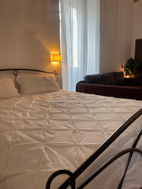 - une chambre avec un lit blanc et un canapé dans l'établissement Rome s Suite Bramante, à Rome