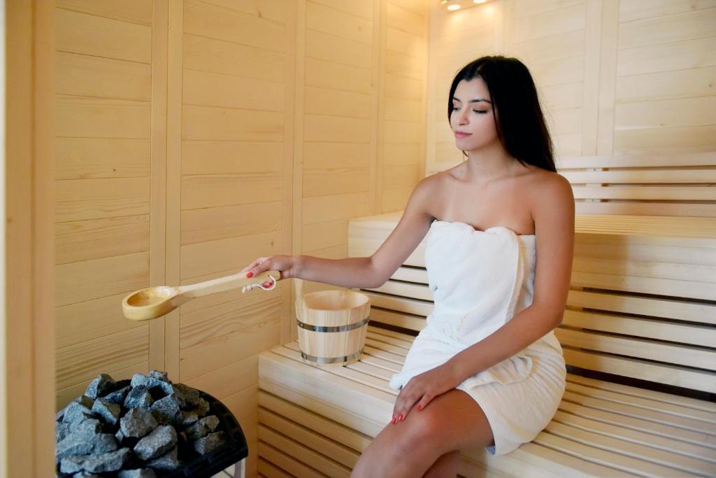 una donna seduta in una sauna con un cucchiaio di legno di 10GR Boutique Hotel & Wine Bar a Città di Rodi