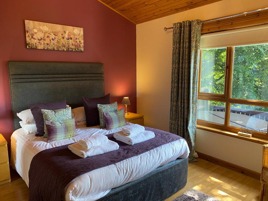 1 dormitorio con cama con almohadas y ventana en Silver Birch Lodge with Hot Tub, en Cupar