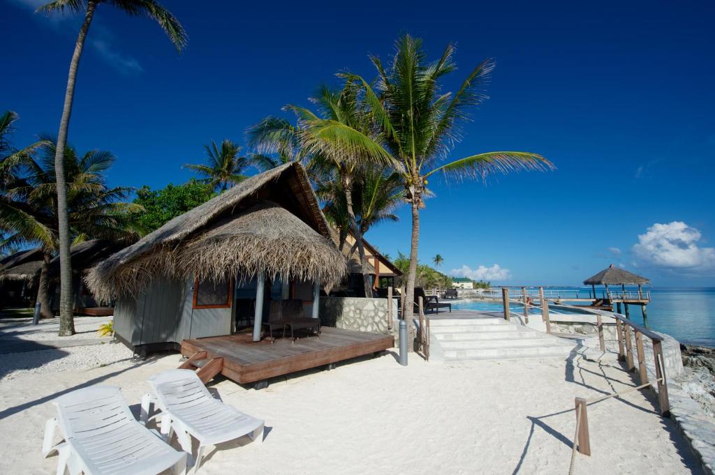 a resort on the beach with chairs and palm trees at Maitai Rangiroa in Avatoru