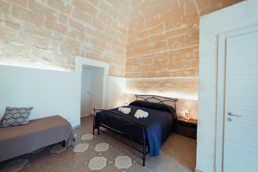 1 dormitorio con 1 cama en una habitación con una pared de ladrillo en Le Dimore nel Cortile con patio e parcheggio privato en Matera