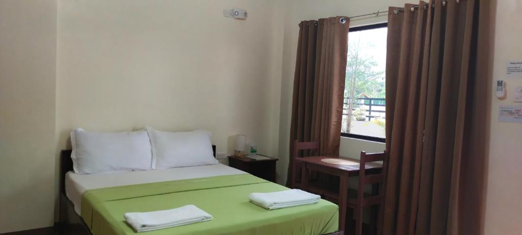 Schlafzimmer mit einem Bett mit grüner Bettwäsche und einem Fenster in der Unterkunft ALTHEA BIRDS NEST INN in Moalboal
