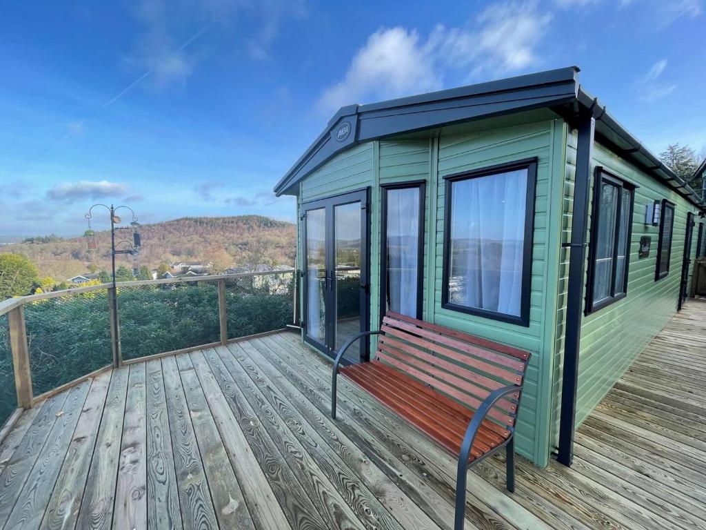 a green tiny house with a bench on a deck at Pass the Keys Beautiful 2BR In Kippford With Incredible Views in Palnackie