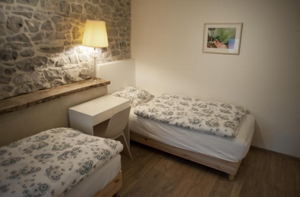 um pequeno quarto com 2 camas e um candeeiro em Les Myosotis em Assesse