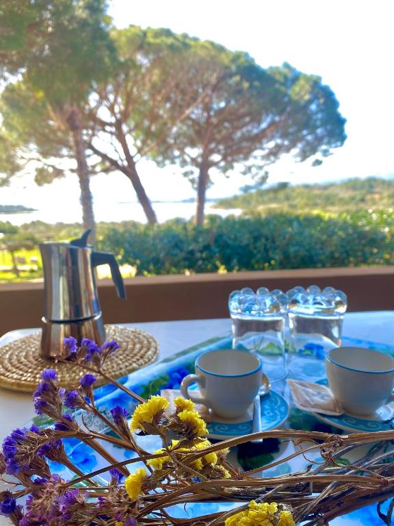 a table with cups and glasses and flowers on it at Residence Porto Coda Cavallo in San Teodoro