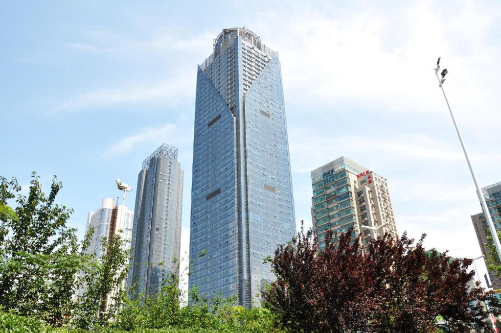 Un haut gratte-ciel au milieu d'une ville dans l'établissement New Century Hotel Qingdao, à Huangdao