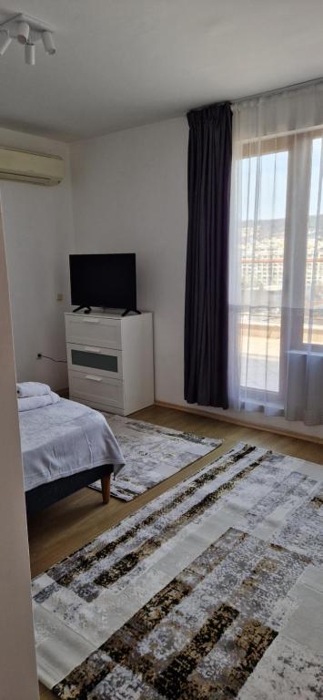 a bedroom with a bed and a television and a window at Студио Тони 1 in Varna City