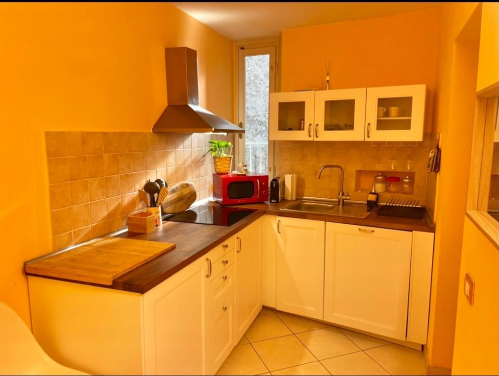 cocina con paredes amarillas, armarios blancos y fregadero en Piazza Napoleone Sweet apartment, en Lucca