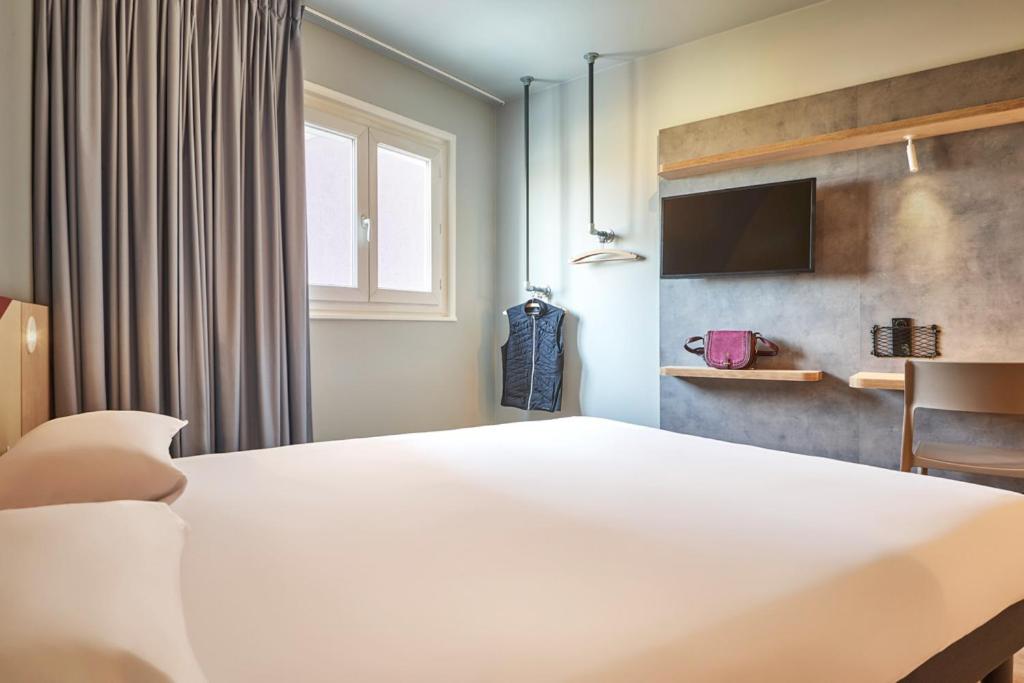 a bedroom with a large white bed and a television at ibis budget Paris Porte d'Aubervilliers in Aubervilliers