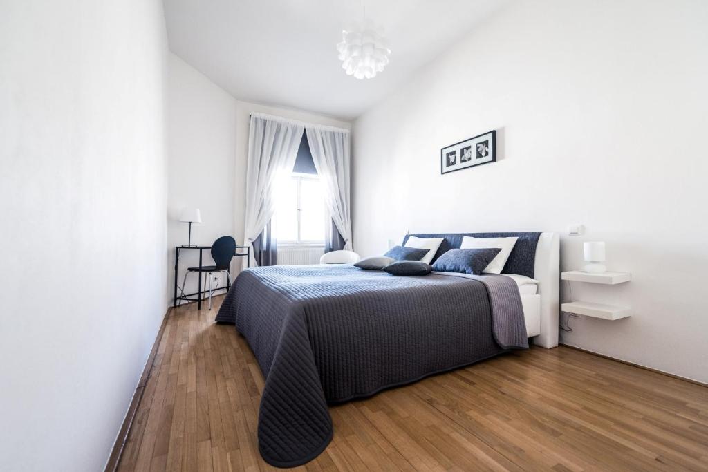 1 dormitorio blanco con 1 cama y suelo de madera en Modern Apartment Riegrovy sady, en Praga