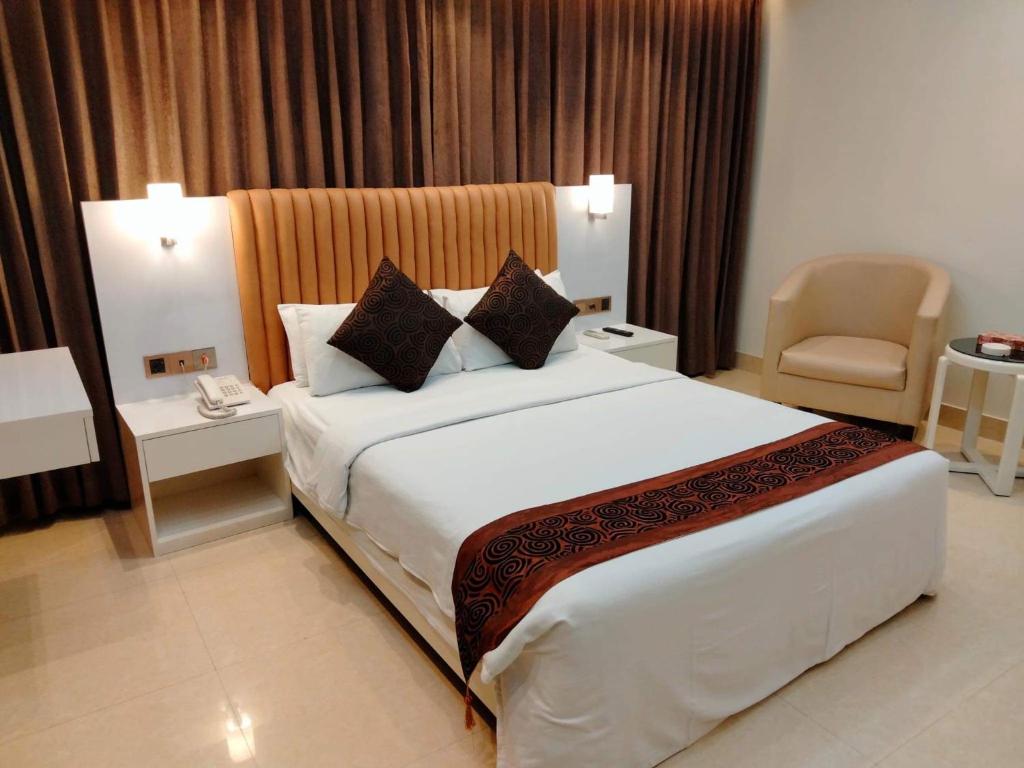 una camera d'albergo con un grande letto e una sedia di White Orchid a Cox's Bazar