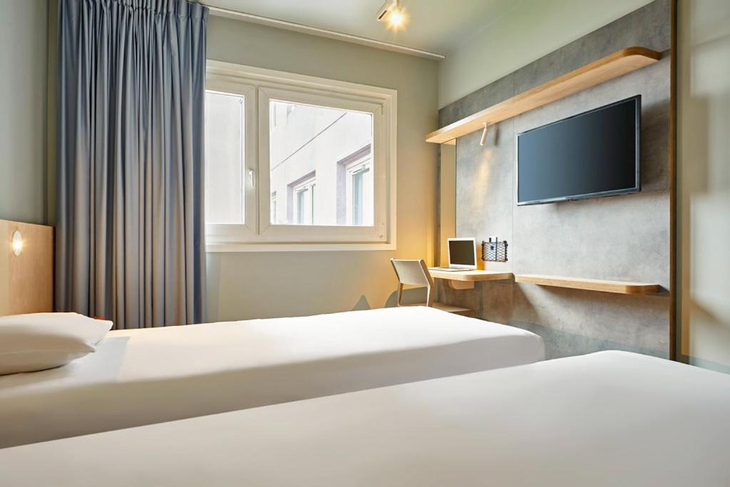 une chambre d'hôtel avec deux lits et une télévision à écran plat dans l'établissement ibis budget Paris Porte d'Aubervilliers, à Aubervilliers
