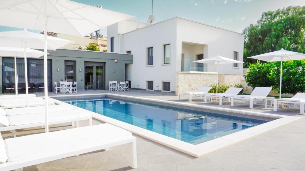 una piscina con sillas blancas y sombrillas junto a una casa en Dimora Giulia, en Bari