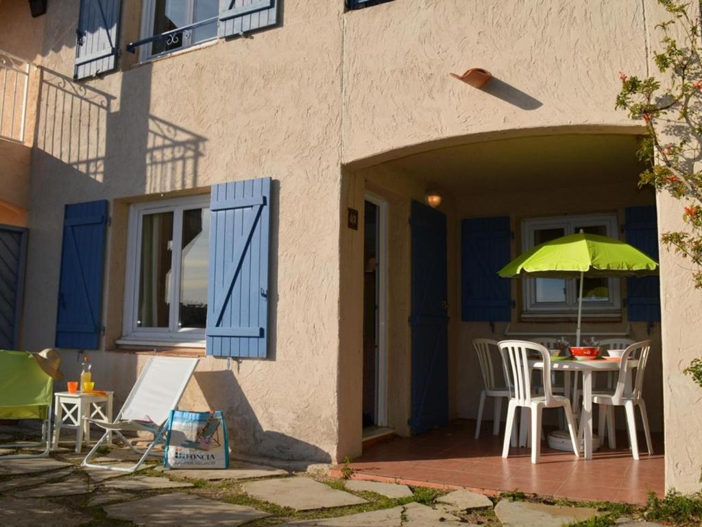 d'une terrasse avec une table et un parasol vert. dans l'établissement Les Issambres : Appt avec Piscine, Tennis, et Parking au Rez de Jardin - FR-1-226-380, aux Issambres