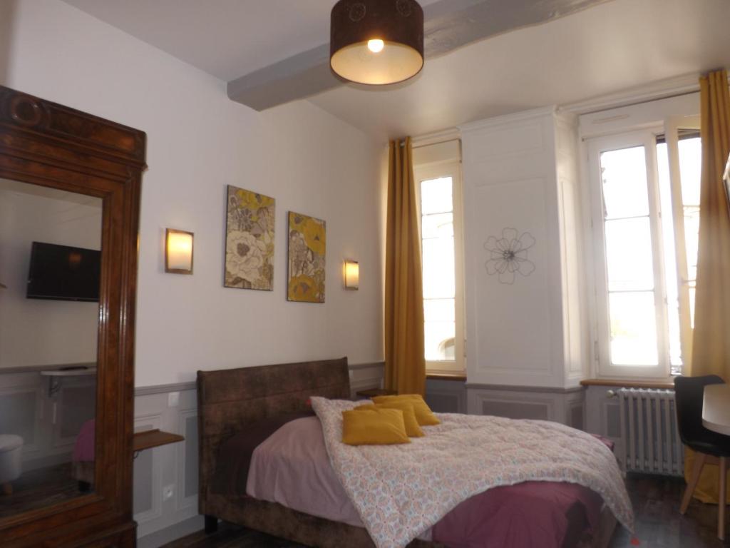 a bedroom with a bed with yellow pillows on it at Chambre d'hôtes LARIBOISIERE in Fougères