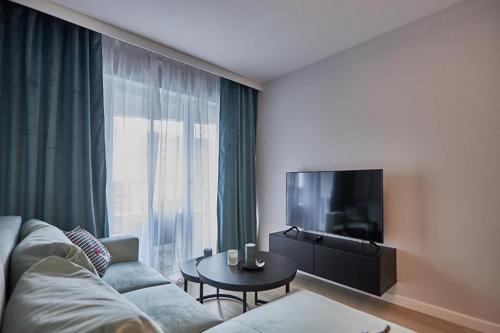 ein Wohnzimmer mit einem Sofa, einem TV und einem Tisch in der Unterkunft Apartamenty Świnoujście - Sun Towers 90 in Świnoujście