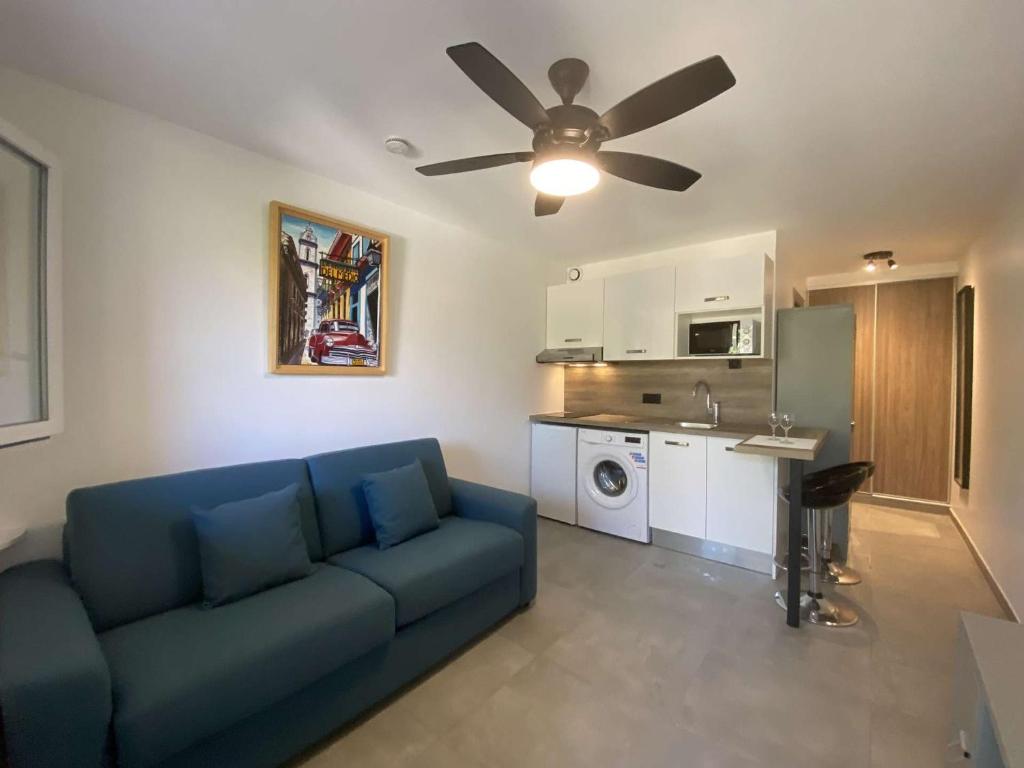 - un salon avec un canapé bleu et un ventilateur de plafond dans l'établissement Studio climatisé avec terrasse, piscine et parking sécurisé - Les Issambres (83), 2 couchages - FR-1-226-494, à Saint-Peïre-sur-Mer