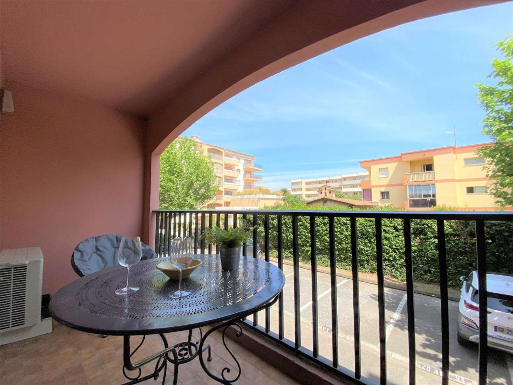 - un balcon avec une table et des verres à vin dans l'établissement Sainte-Maxime, Apt 2 pièces avec piscine, terrasse, parking privé, proche plage et commerces - FR-1-226-487, à Sainte-Maxime