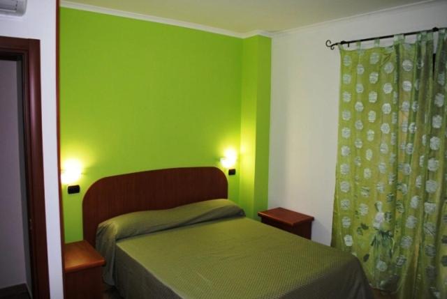Dormitorio verde con cama y ducha en B&B Insula Portus, en Fiumicino