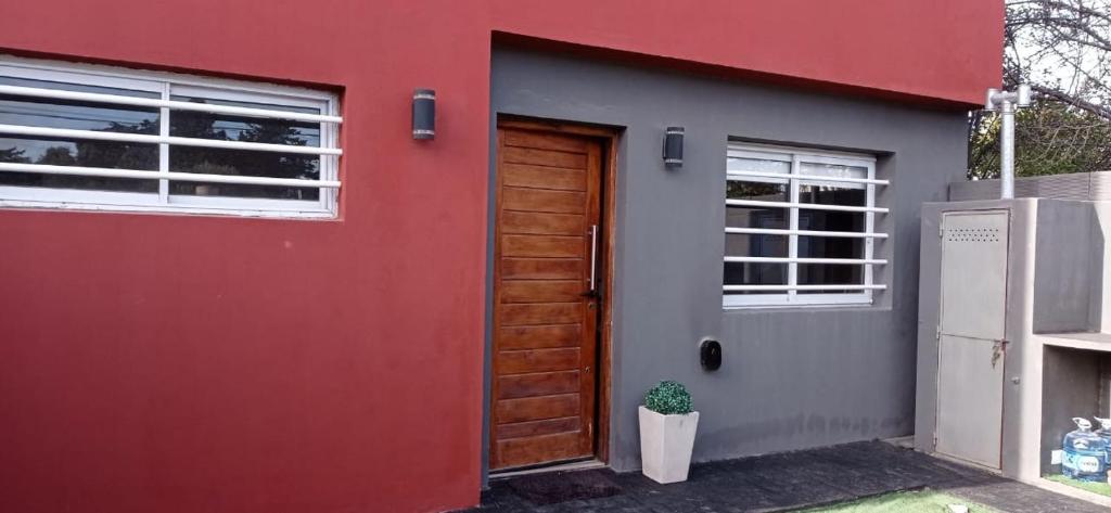 una casa roja y gris con una puerta roja en HERMOSO DÚPLEX NECOCHEA en Necochea