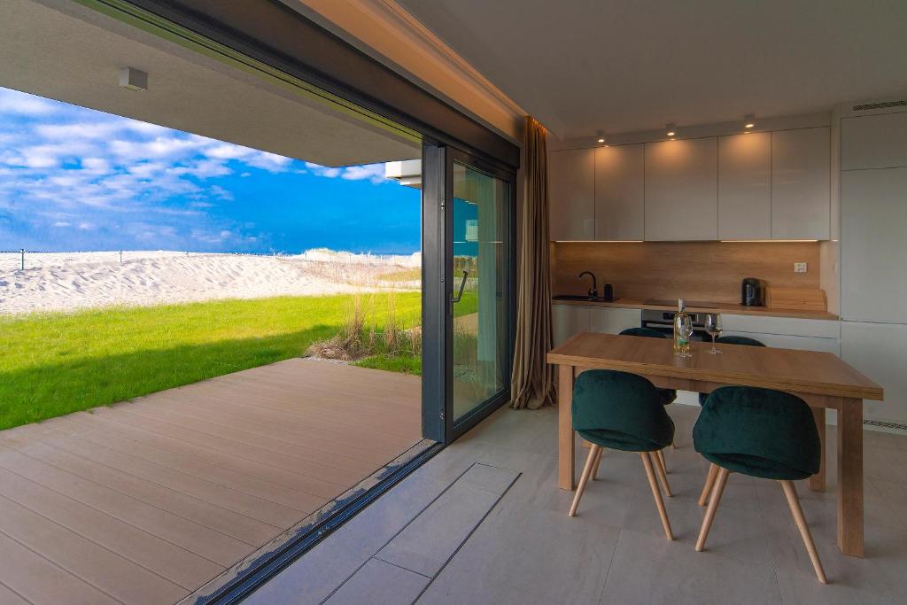 Una cocina con una mesa de madera y dos sillas. en Apartament ODNOWA z bezpośrednim widokiem na morze w Gardenia Dziwnów -, en Dziwnów