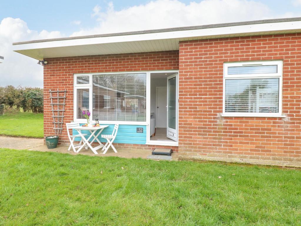 a red brick house with a table and a window at 12 Siesta Mar in Norwich