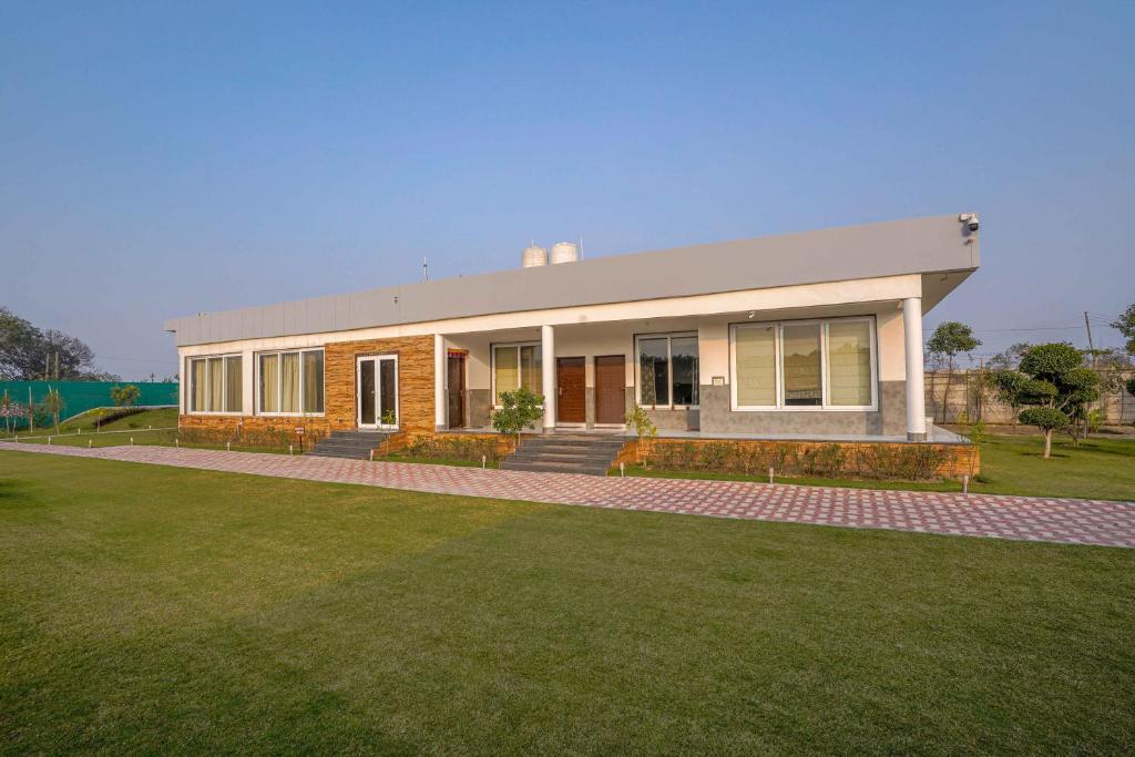 a house with a lawn in front of it at Luxury Farmhouse Stay, Pure Vegetarian- Santushti Farm, NCR in Tibri